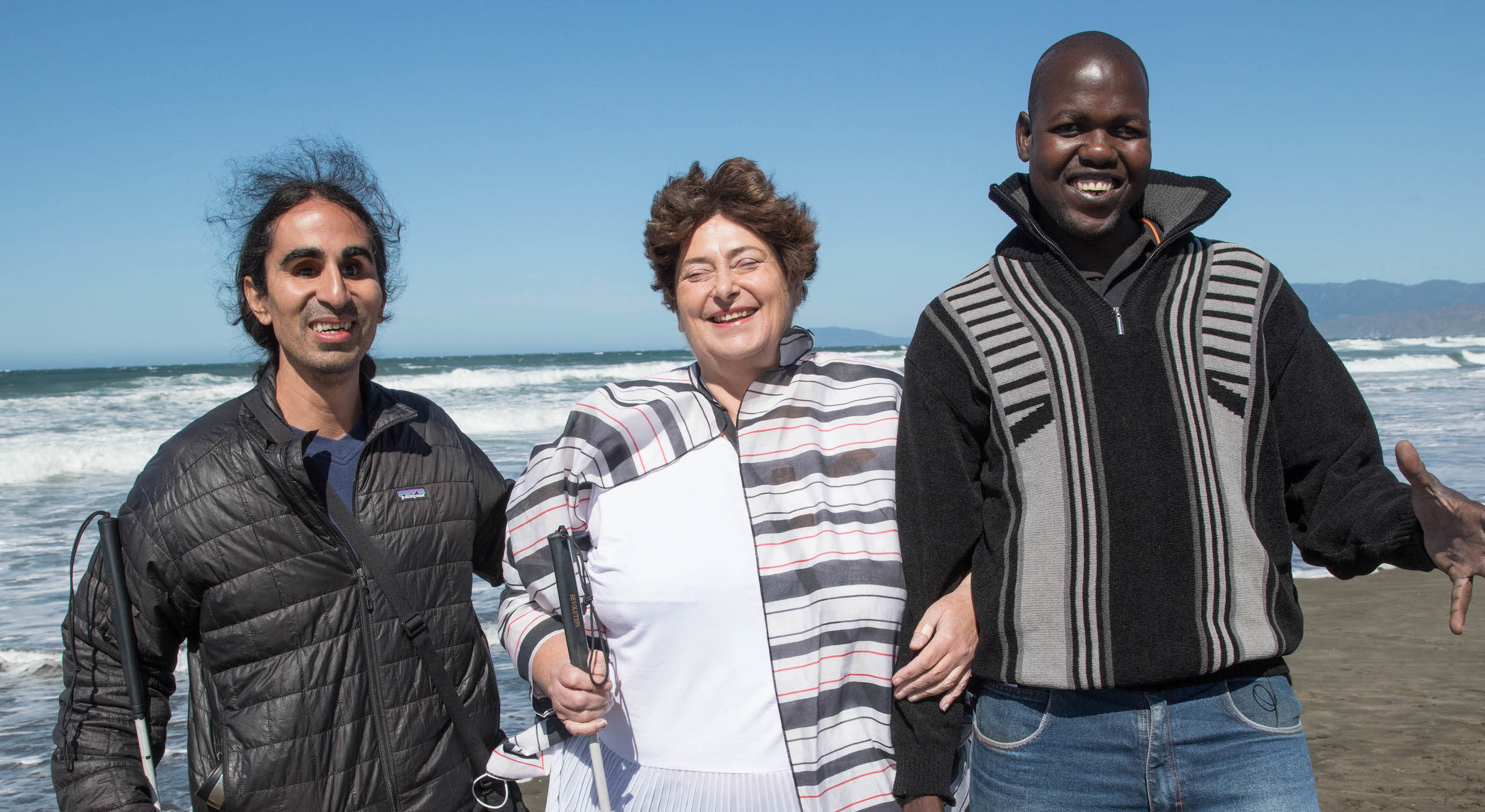 Holman Prizewinners Ahmet Ustunel, Ojok Simon and Penny Melville-Brown stand together on Ocean Beach.