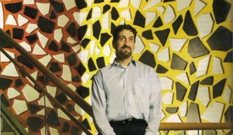 Albert Rizzi in front of a mosaic covered wall.