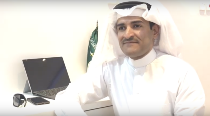 Abdullah Aljuaid sits at a desk in front of his computer.
